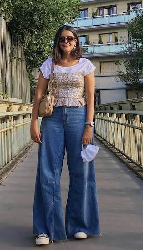 Pantalona jeans com tênis para look com camiseta branca e top de paetê